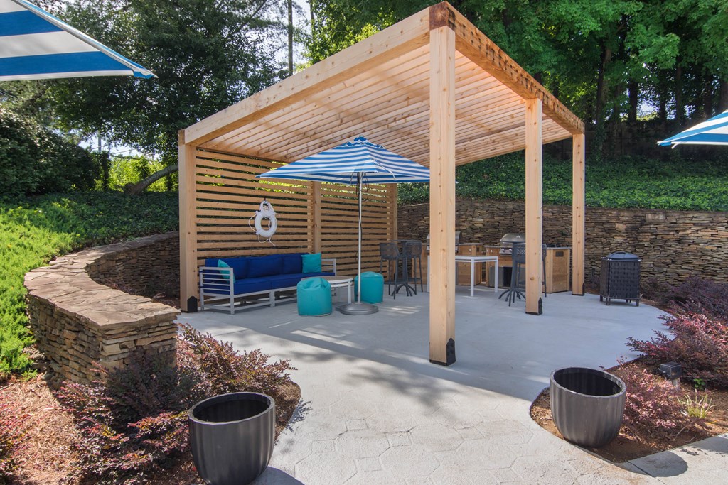 a wooden pavilion with a patio with benches and umbrellas