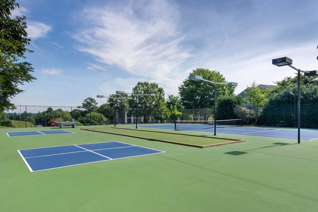 two tennis courts with lights on them on a sunny day