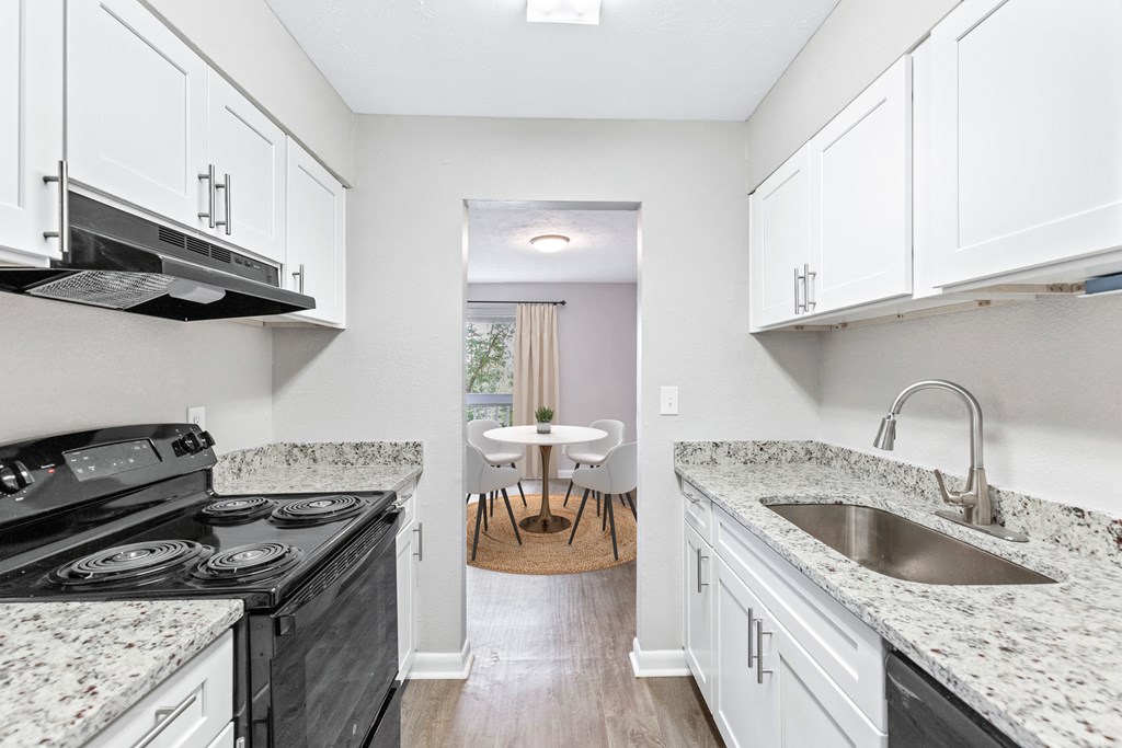 a renovated kitchen with marble counter tops and white cabinets