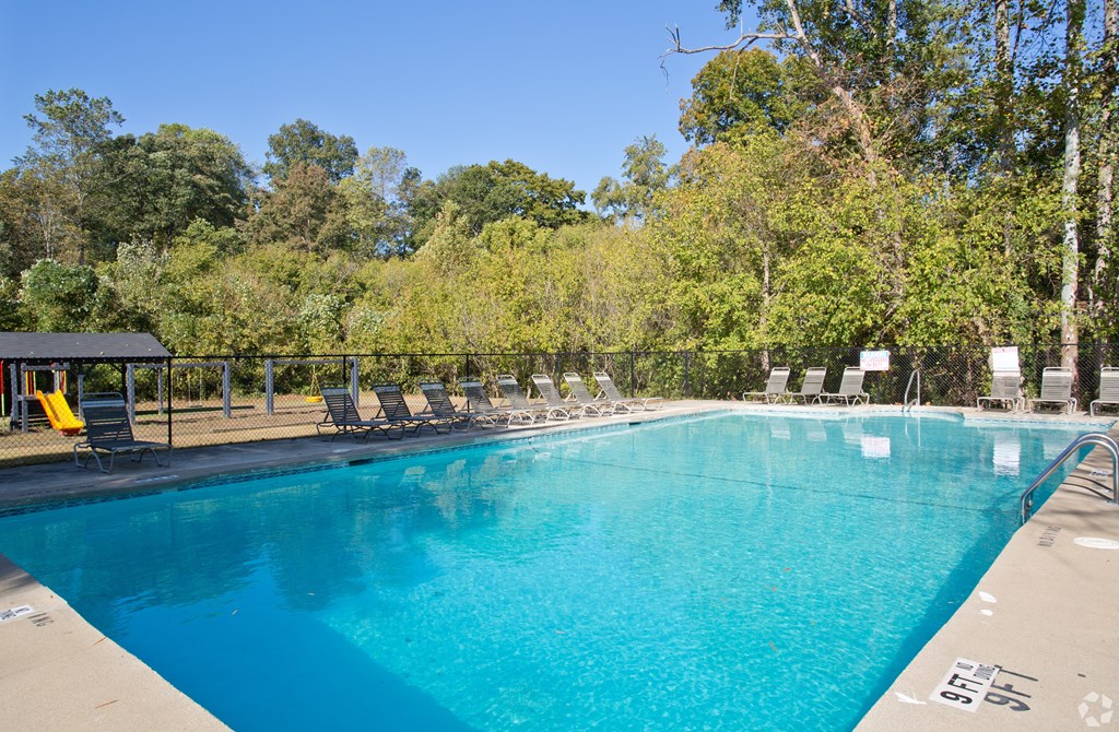 A large swimming pool with a blue tinted water and a yellow chair.
