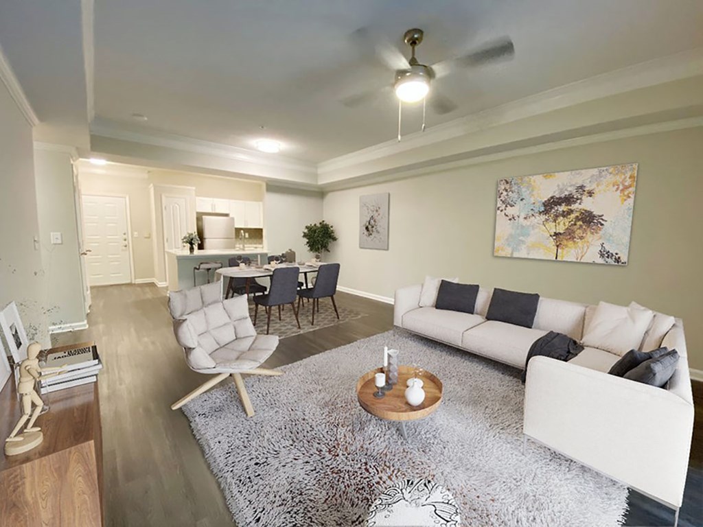 A living room with a white couch, a grey rug, and a ceiling fan.
