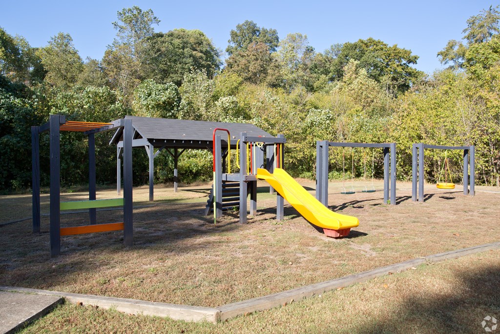 A playground with a yellow slide and a red and yellow climbing frame.