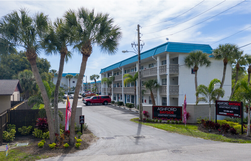 Main entrance sign to Ashford Bayside Apartments in Kenneth City, FL, surrounded by beautiful landscaping