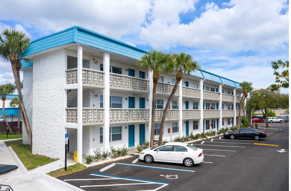 A view of a three-story apartment building at Ashford Bayside and parking space from across a street
