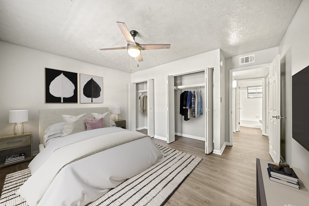 A bedroom with a bed, a ceiling fan, and a hallway.