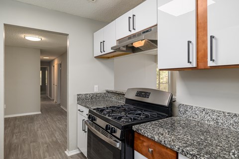 A kitchen with a black stove top oven and white cabinets.