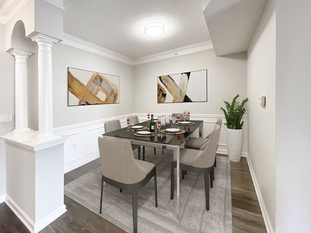 A dining room with a table set for two and a potted plant.