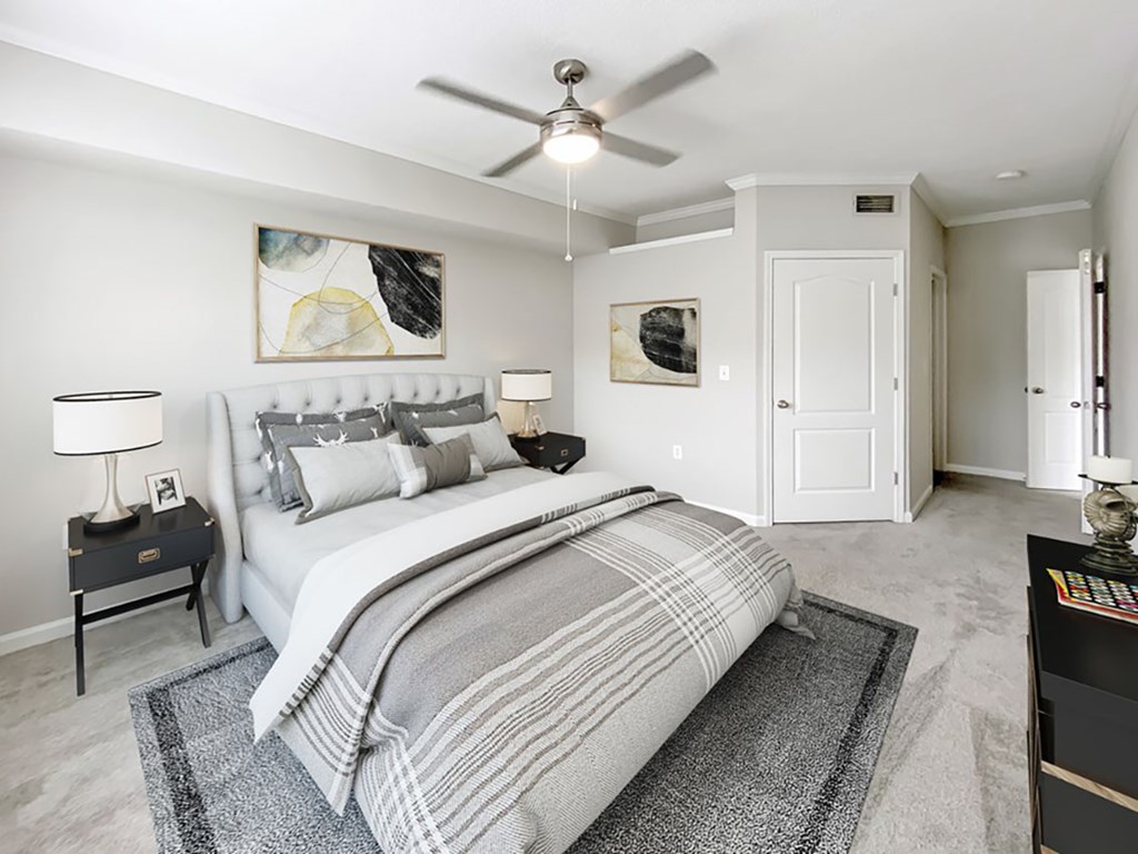 A bedroom with a large bed and a ceiling fan.