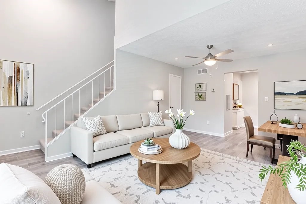 A living room with a white couch, a wooden coffee table, and a ceiling fan.