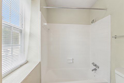 A white bathroom with a tub and a window.