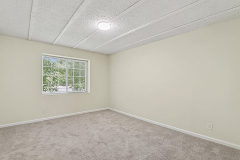 A room with a window and carpeted floor.