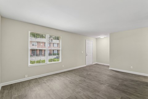 A room with a white door and a window showing a building outside.