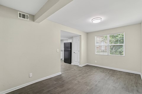 A room with a doorway leading to another room and a window with blinds.