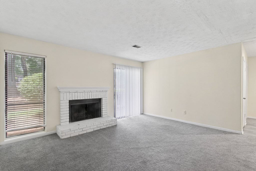A living room with a fireplace and a carpeted floor.