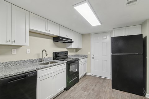 A kitchen with black appliances and white cabinets.