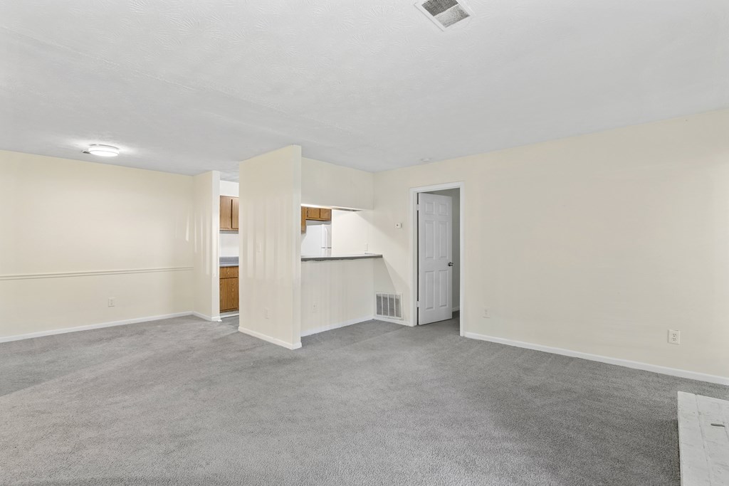 A large, empty room with a carpeted floor and white walls.