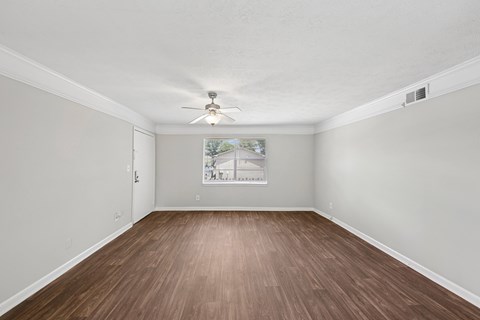 Empty room with wood flooring and a ceiling fan.
