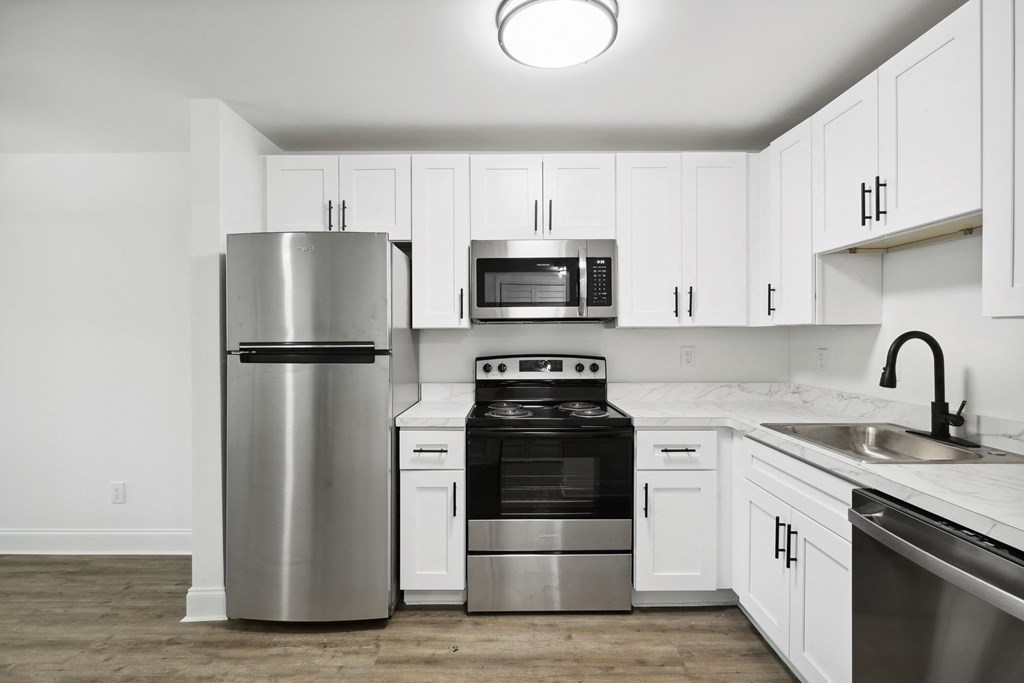 a white kitchen with stainless steel appliances and white cabinets
