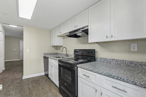A kitchen with a black stove top oven and white cabinets.