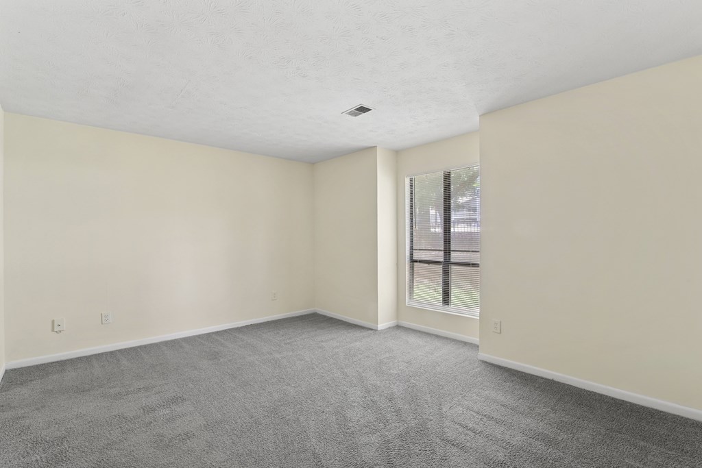 A room with a carpeted floor and a window.