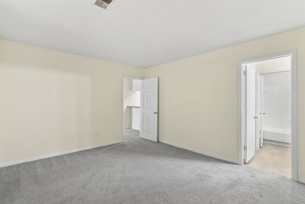 A room with a carpeted floor and two open doors.