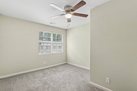A room with a ceiling fan and a window.