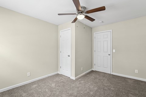 A room with a ceiling fan and two doors.