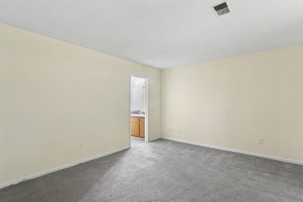 A room with a carpeted floor and a doorway leading to another room.