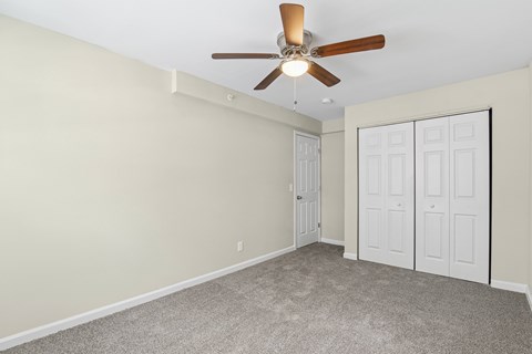 A room with a ceiling fan and carpeted floor.
