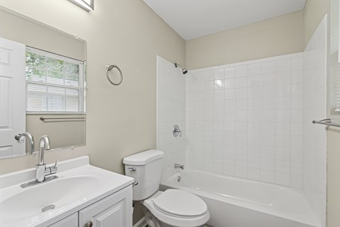 A white bathroom with a toilet, sink, and bathtub.