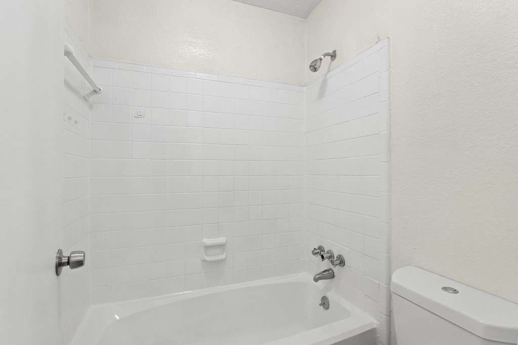 A white bathroom with a tub and toilet.