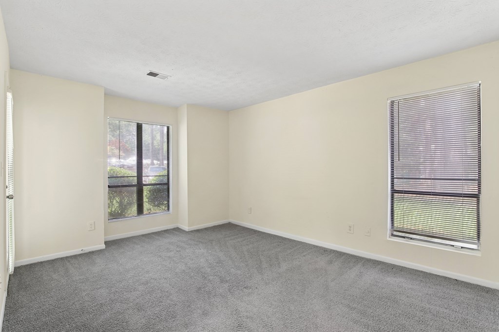 A room with a carpeted floor and a window with blinds.