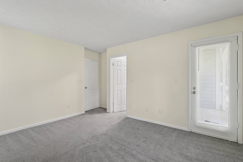 A room with a carpeted floor and two doors.