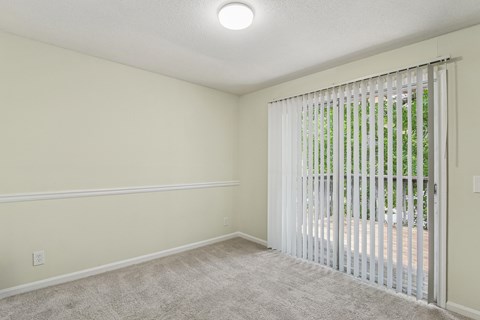 A room with a carpeted floor and a window with blinds.