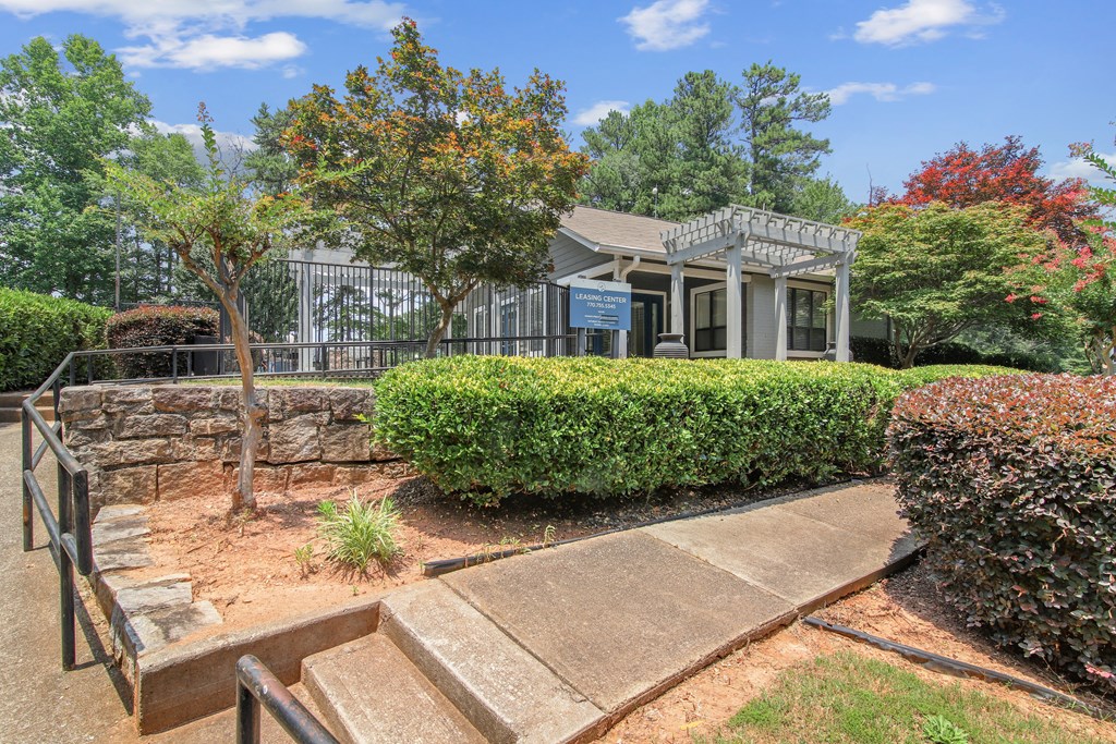 A small building with a porch is surrounded by a well-kept garden.