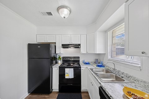 A black fridge and oven in a white kitchen.