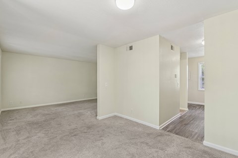 A spacious empty room with carpeted floor and white walls.