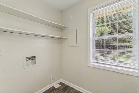 A room with a window covered by white blinds.