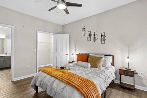 A bedroom with a bed, nightstand, and a ceiling fan.