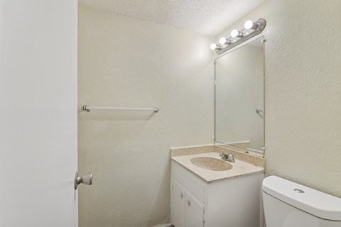 A white bathroom with a toilet, sink, and mirror.