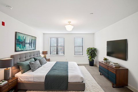 A bedroom with a large bed and a flat screen TV mounted on the wall.