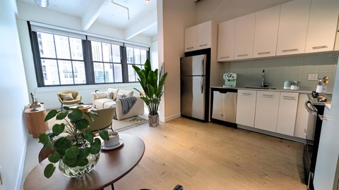 A kitchen with white cabinets and a black fridge is shown.