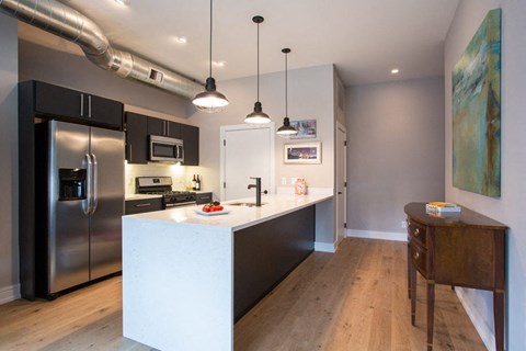 a kitchen with a large island and a stainless steel refrigerator