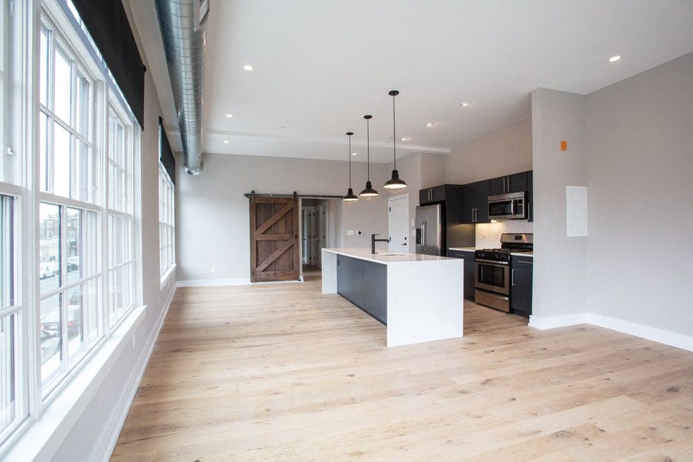 an open kitchen and living room with wood flooring and a large window