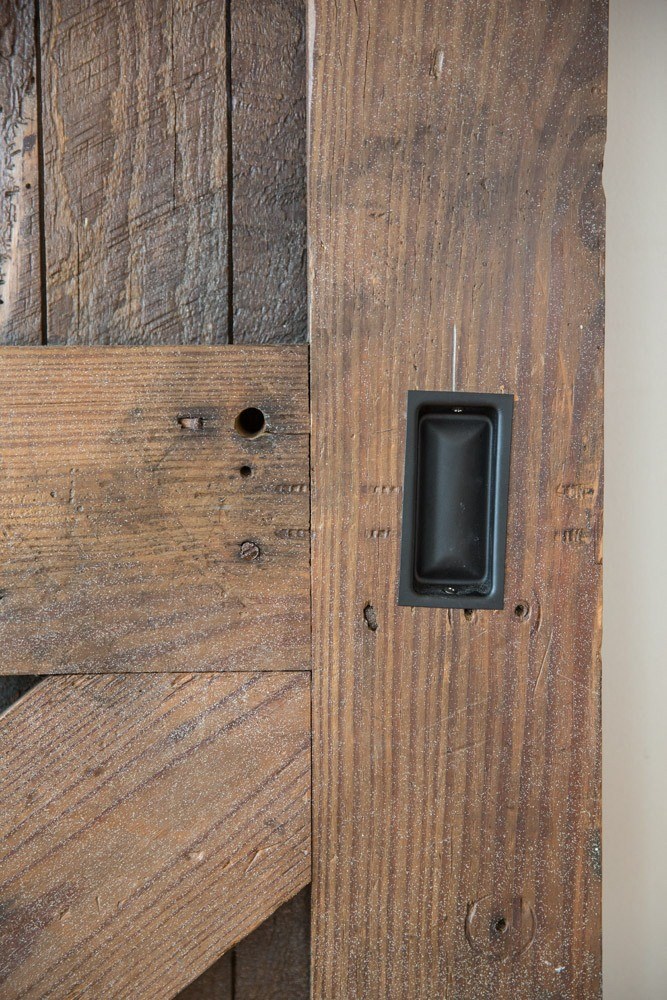 a wood door with a black handle on a wooden wall