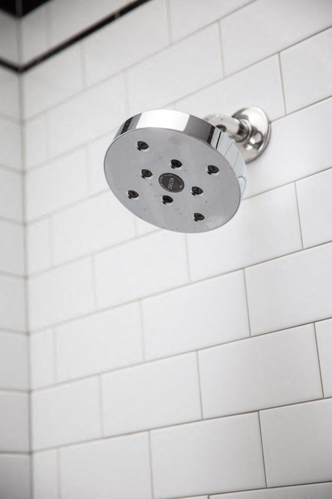 a shower head in a white tiled bathroom