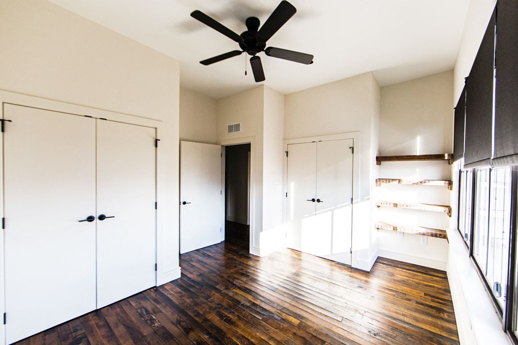 an empty room with white closets and a ceiling fan