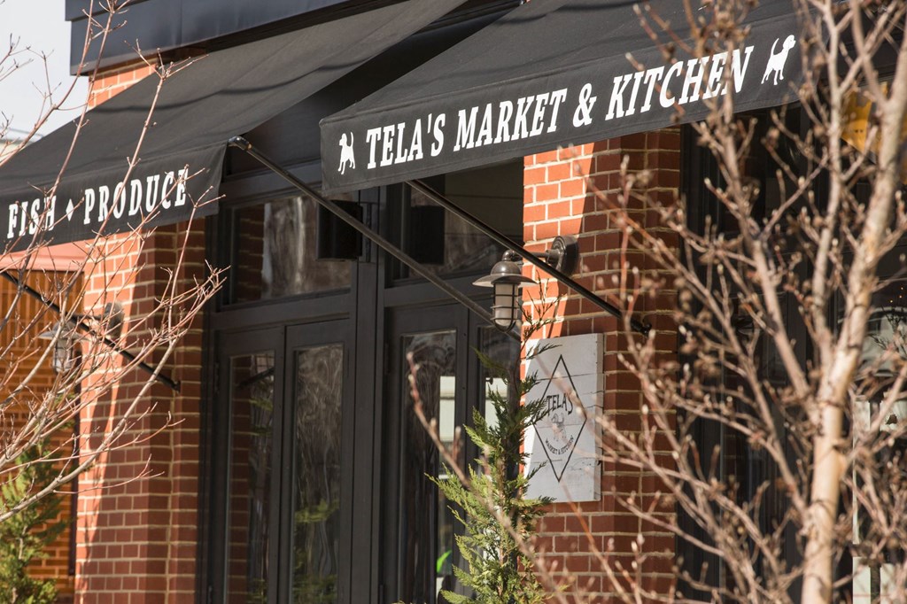 the front of a retail store with a black awning and a sign for