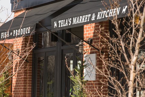 the front of a retail store with a black awning and a sign for