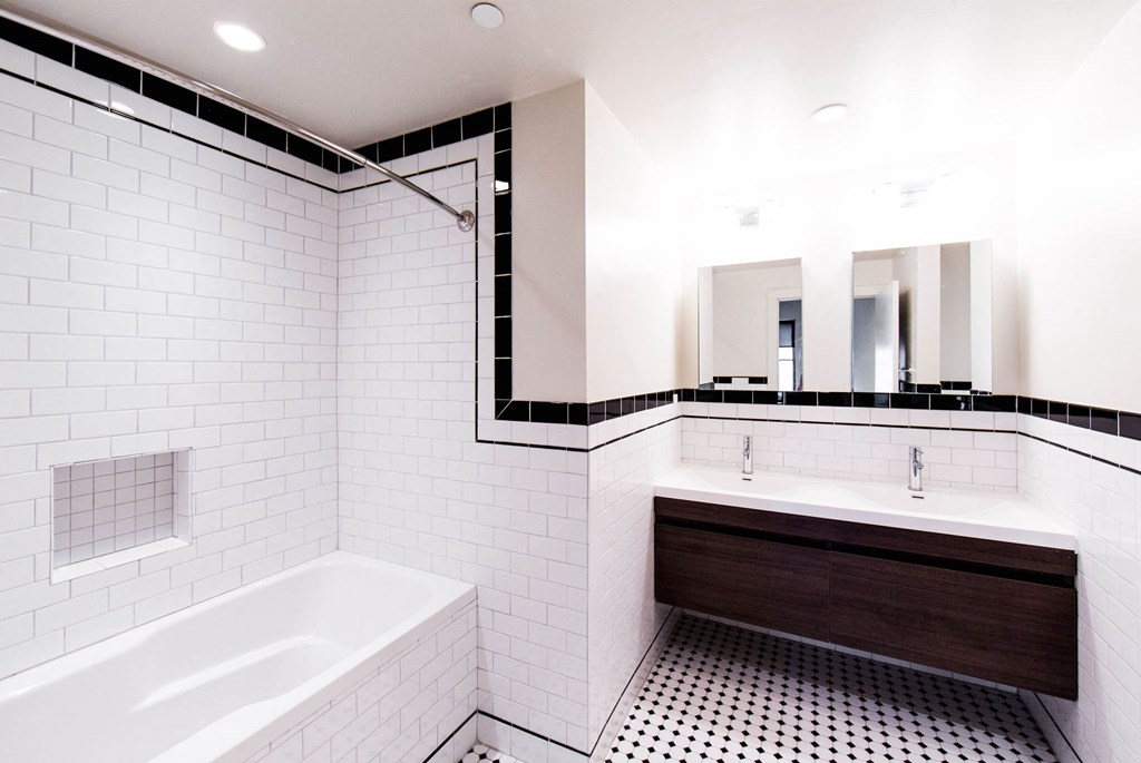 a bathroom with white tiles and a tub and a sink